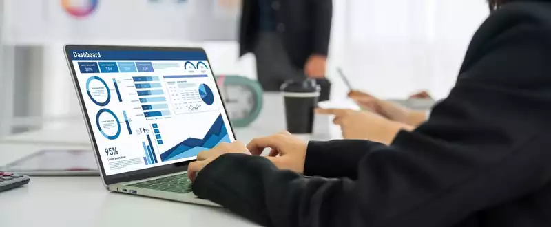 A business man studies a business data dashboard on a laptop.