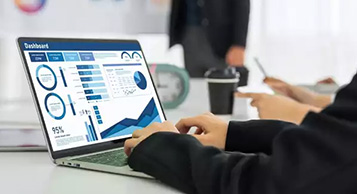 A business man studies a business data dashboard on a laptop.
